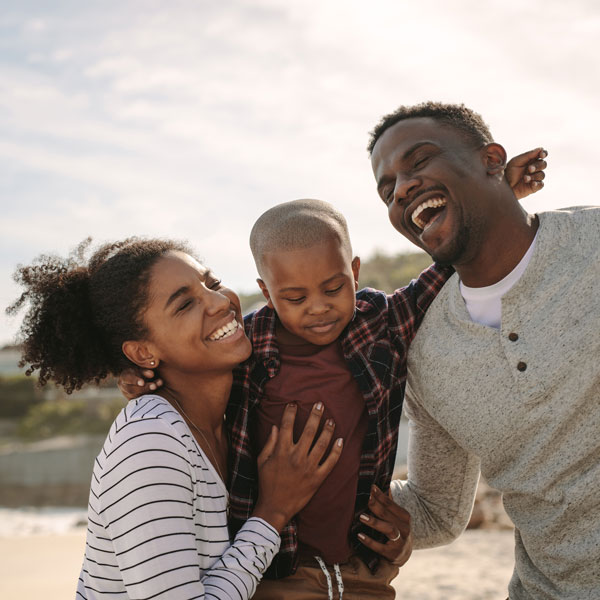 family of three smiling and laughing together outside