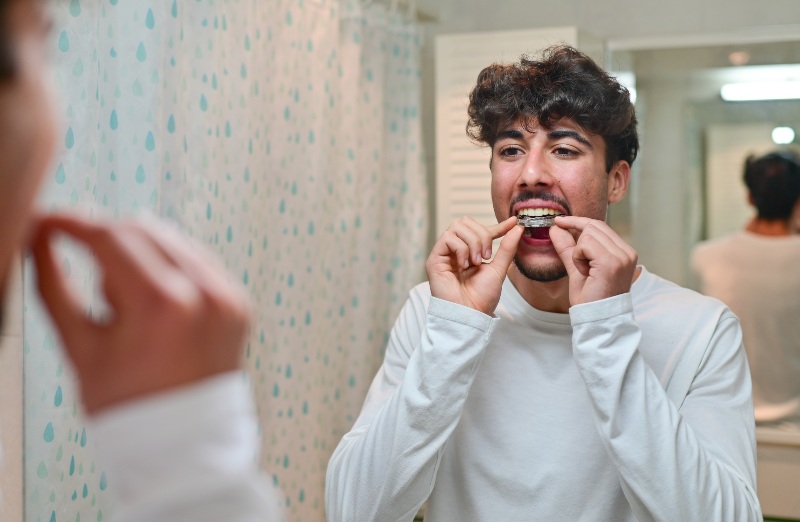 Person inserting a dental nightguard at home to protect teeth during sleep in New Lenox, IL
