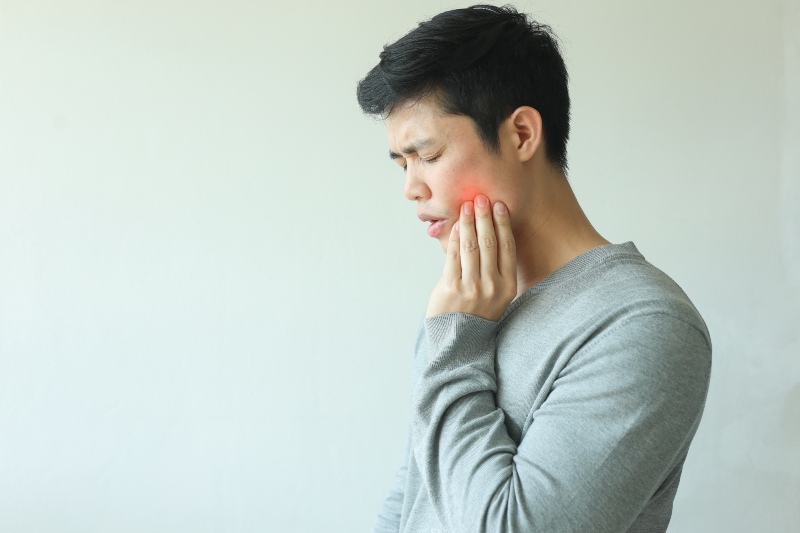 Man holding jaw pain indicating TMJ or TMD symptoms in New Lenox, IL